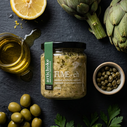 Jar of artichoke spread with artichokes, olives, lemon, and capers on a dark surface