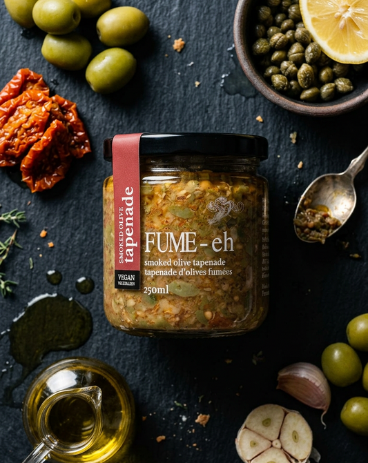 Jar of 'Fume' tapenade with olives, capers, and lemon on a dark surface